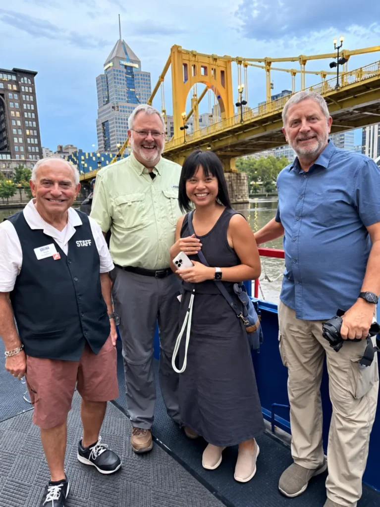 ITMI team and travel professionals posing together with the Pittsburgh skyline and Roberto Clemente